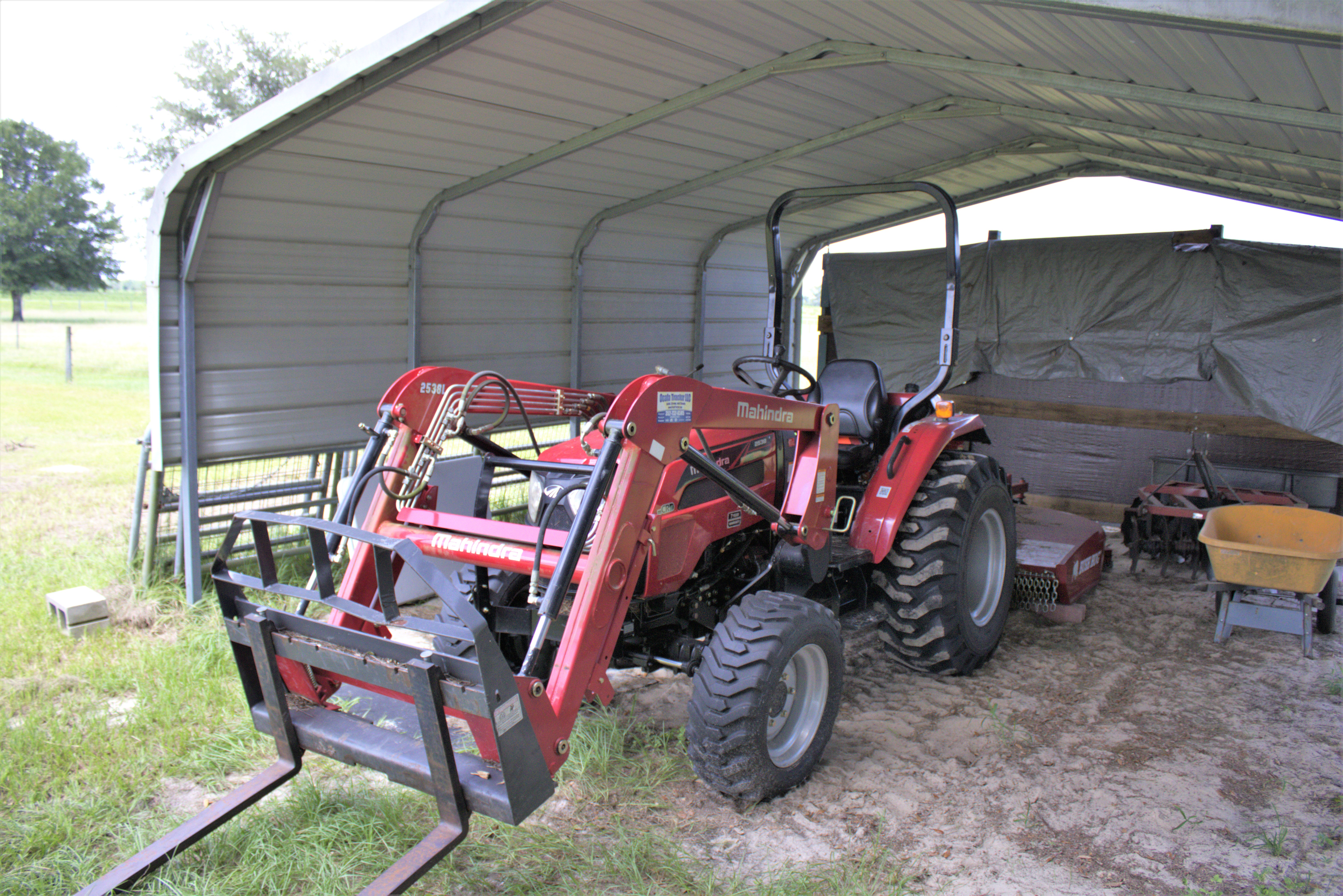Red tractor sitting under awning