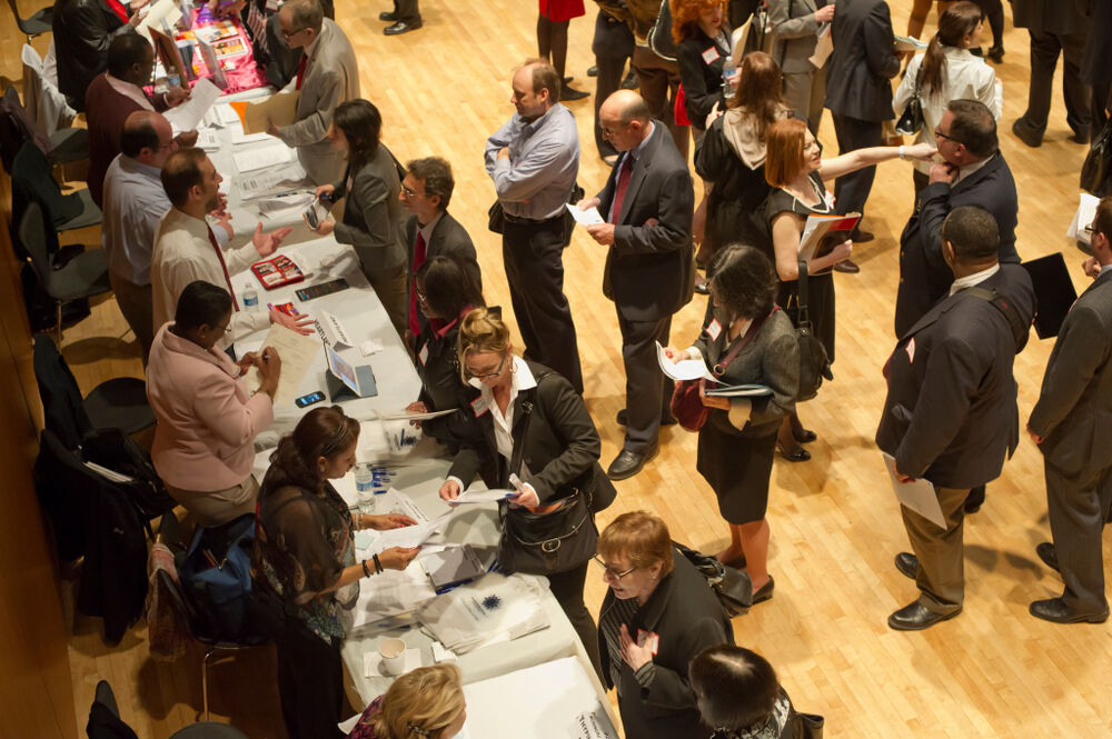 Job seekers speak with employers at job fair