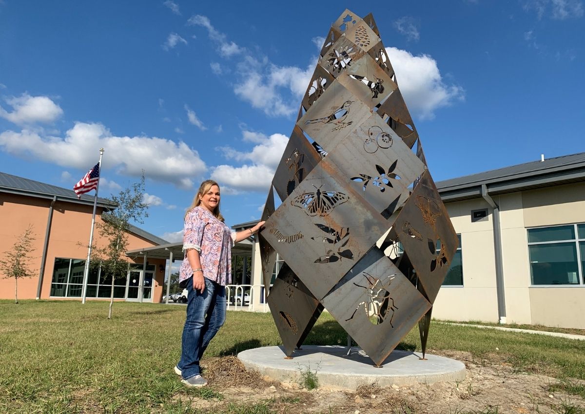 Dr. Cynthia Sanders stands beside outdoor art