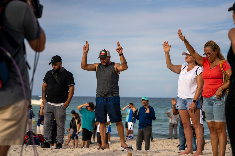 People pray on the beach near the Chaplain Towers collapse