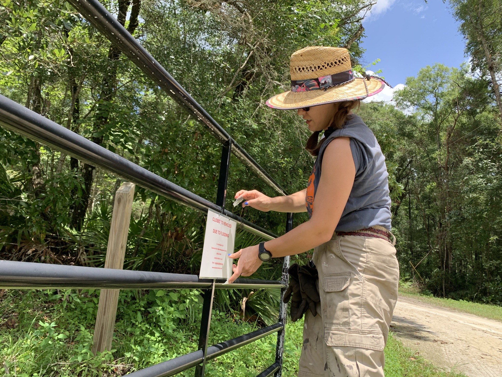 Rachel Townsend hanging a closed sign on a gate at Rock Bluff Springs