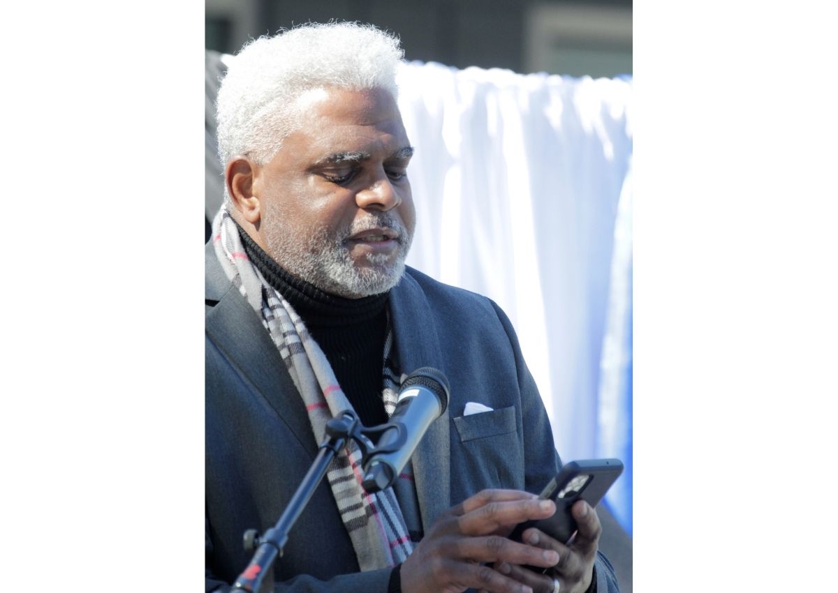 E. Stanley Richardson reads from a phone on stage