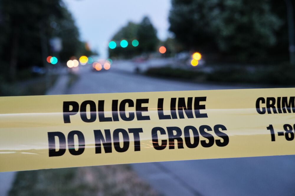 Police yellow tape, blurred lights and traffic accident in background