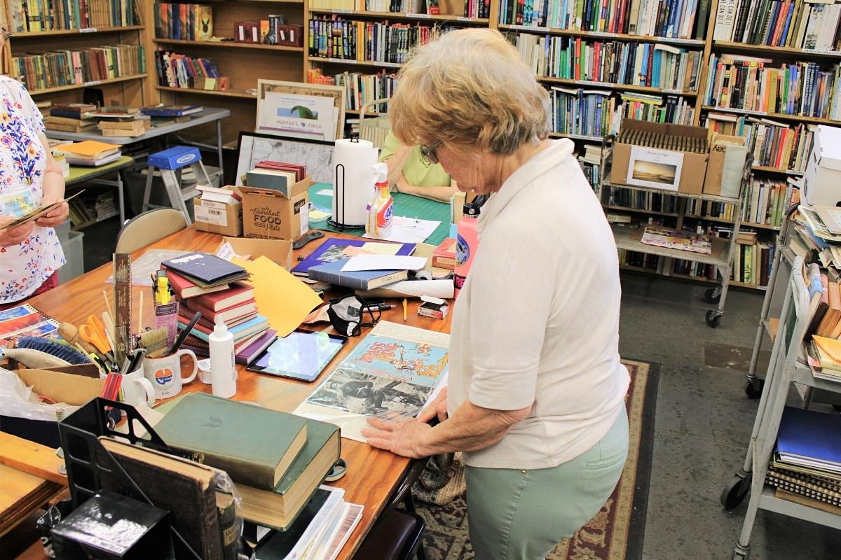 A volunteer attaches a plastic cover to a book