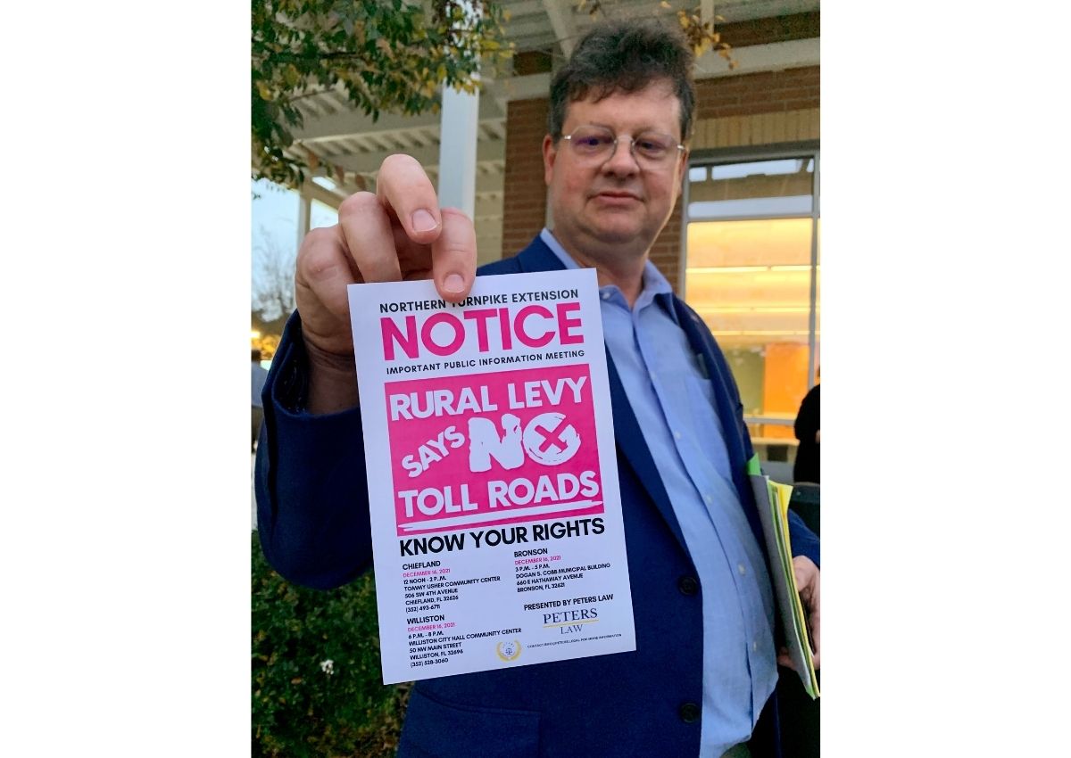 Brandon Peters holds a flyer opposing the proposed Florida's Turnpike extension
