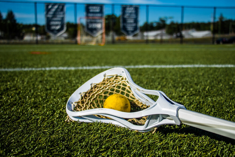 Single yellow lacrosse ball on the grass front of a training net