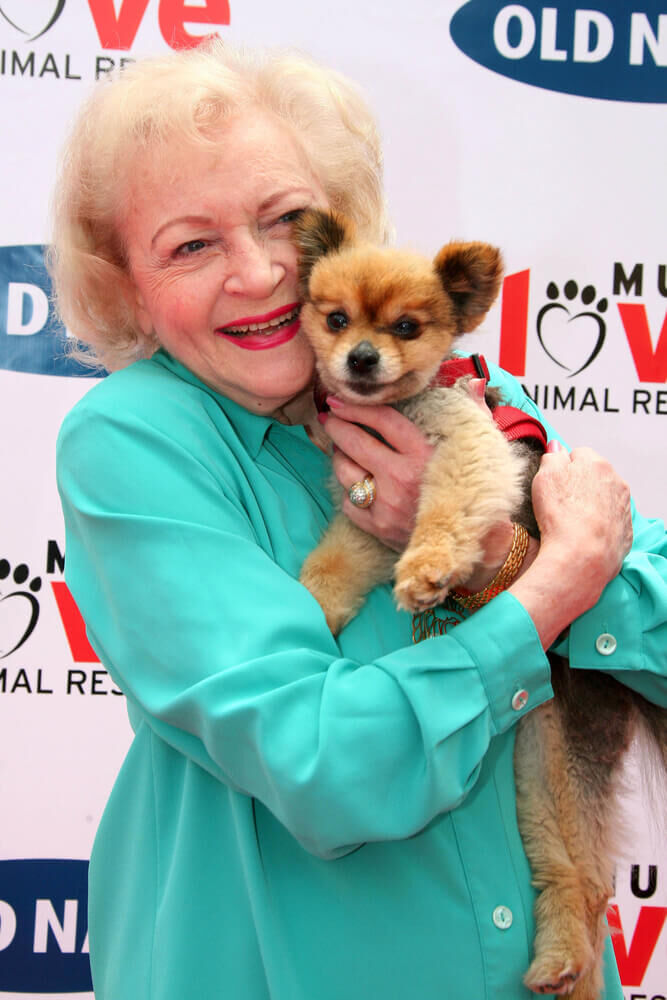 Actress Betty White holds a small dog