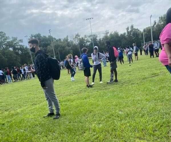 Students in a field waiting on authorities to finish bomb sweep at Newberry High School