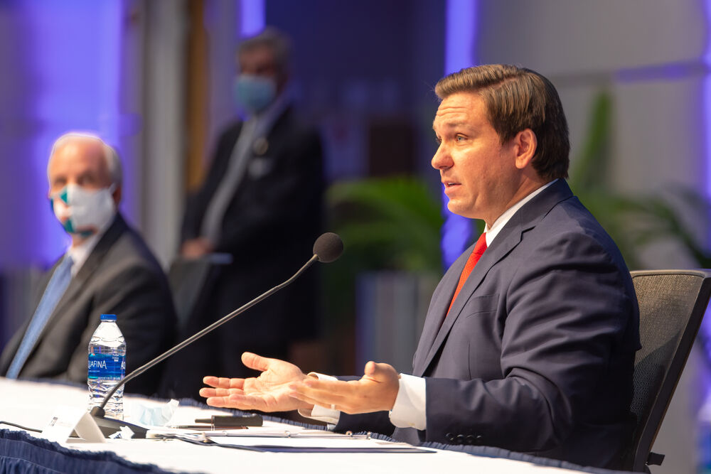 Florida Gov. Ron DeSantis seated behind microphone