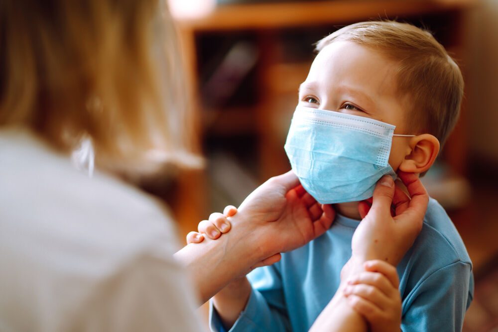 Mom putting on little boy's mask