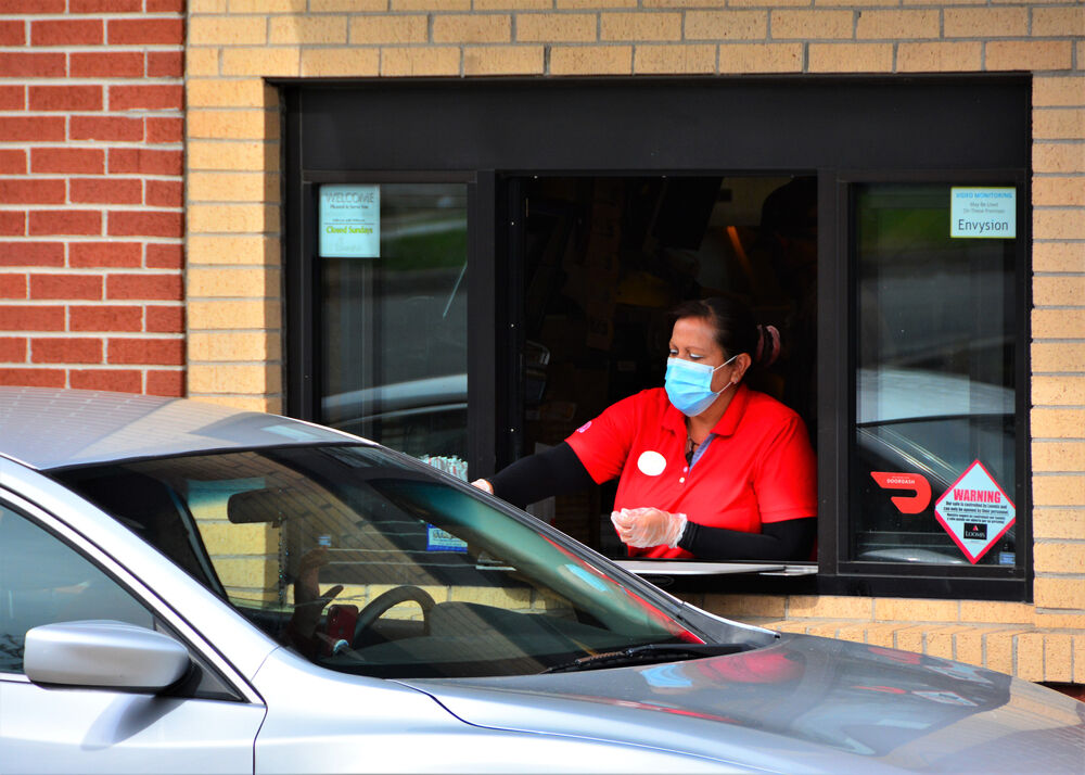 Chick-fil-A associate with mask serves drive-thru patron