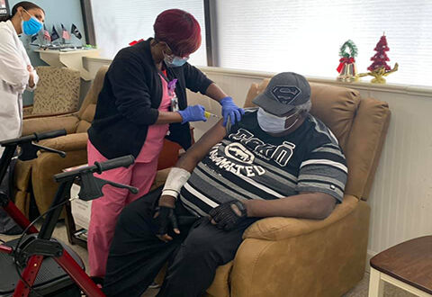 Registered Nurse Stacie Graham administers first COVID-19 vaccine to Army Veteran Wallace Thomas at the Malcom Randall VA Medical Center Community Living Center on Dec. 22.
