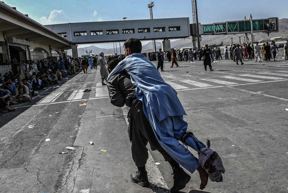 A man carries a wounded person at Hamid Karzai International Airport in Kabul, Afghanistan.