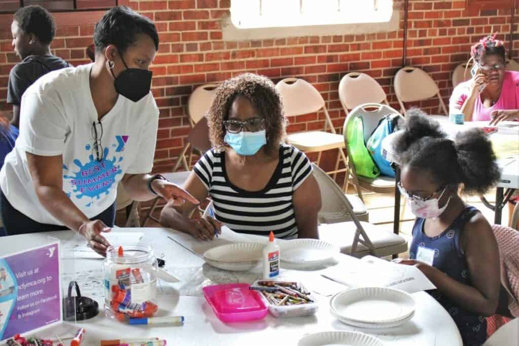 Angela Howard, president of the YMCA of North Central Florida, speaks with an attendee filing out a survey
