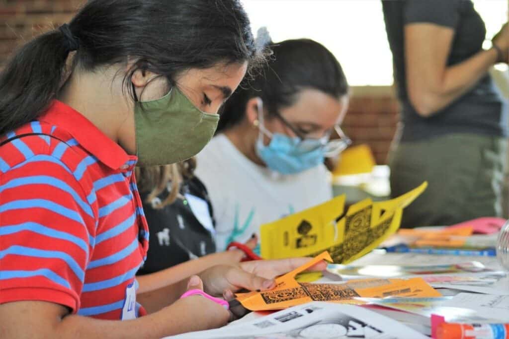 Jaziel cuts out a paper cube at the start of Digital Magic_ Art For Kids.