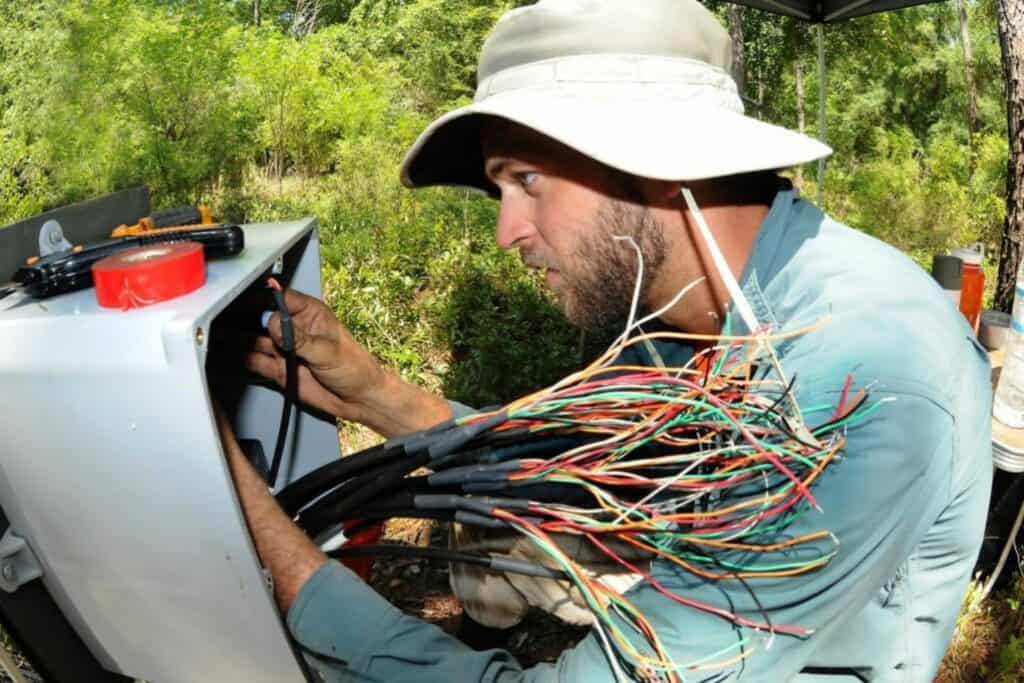 Kenyon Watkins, the senior field technician on the project, working in the field to wire up a soil moisture sensor.