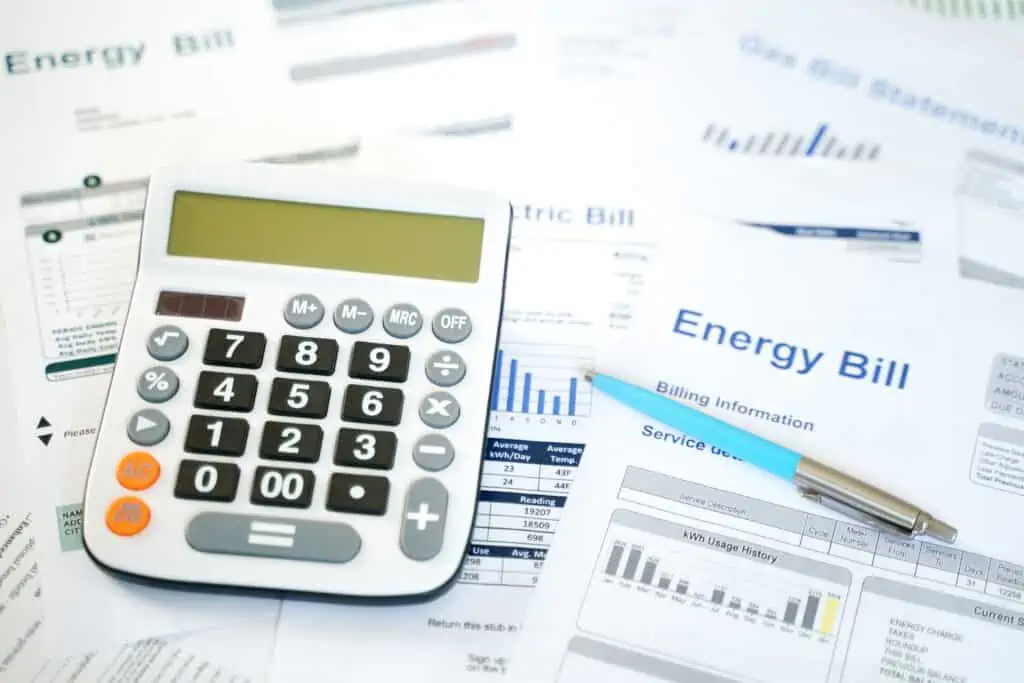 A photo illustration of a stack of electric bills and a calculator