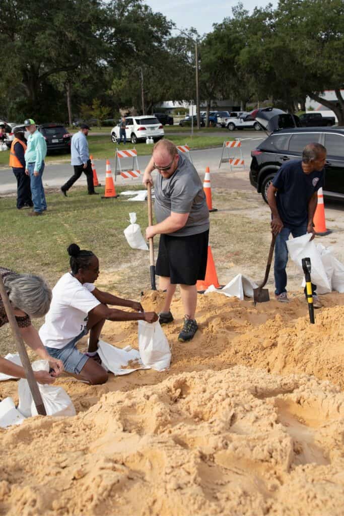 Gainesville resident Matthew Sides, in gray, helps a stranger fill sand bags.