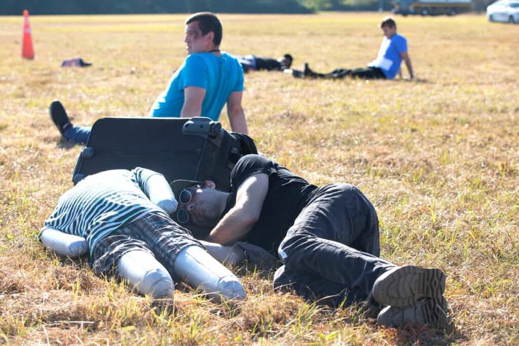 A "victim" seeks shelter from the sun beside a blow-up doll serving as a passenger who suffered a fatal injury.