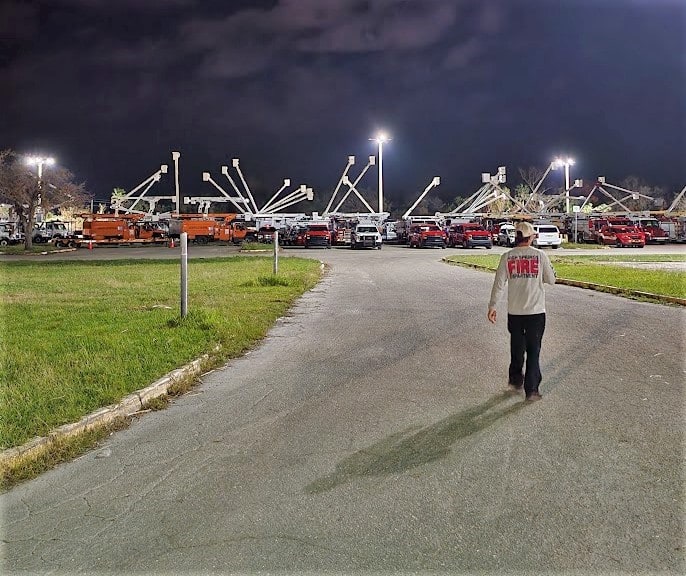 Crews leave utility trucks lined up at a staging area.