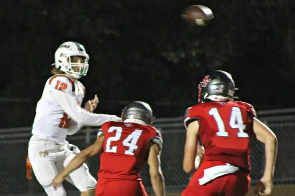 Eastside quarterback Holden Johnson gets a pass off while under pressure from Santa Fe's Ayden Slayton (24) and Ethan Thomas (14) on Friday.