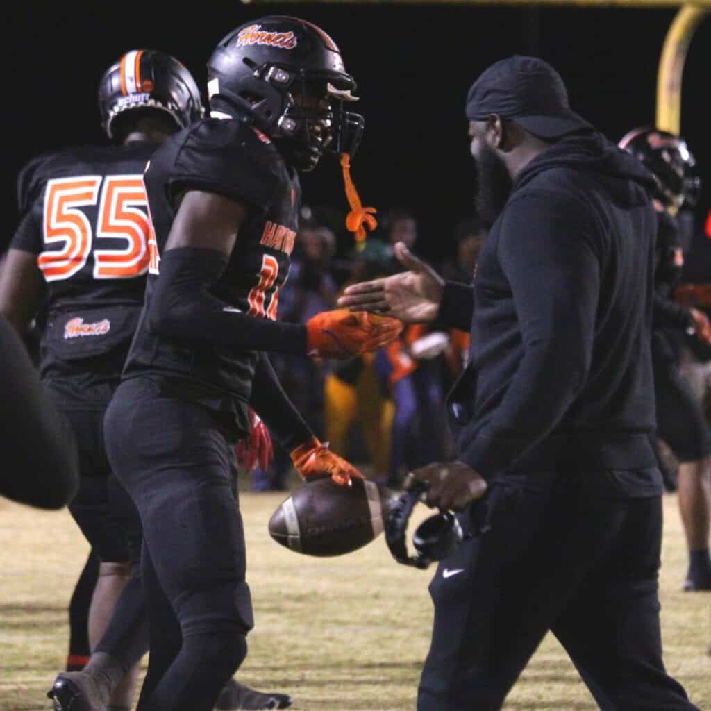 Jalien Ruth celebrates with Hawthorne coach Cornelius Ingram following a third quarter interception return for a touchdown on Friday.