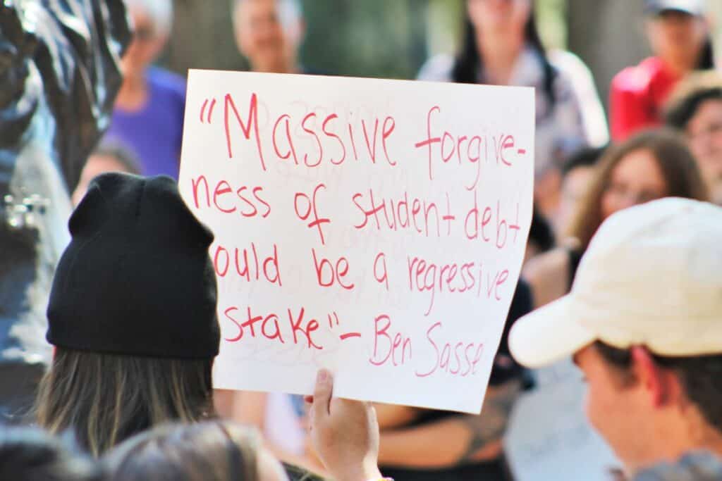 UF student protesters against Sen. Dr. Ben Sasse with student debt forgiveness sign outside Emerson Alumni Hall on Monday.
