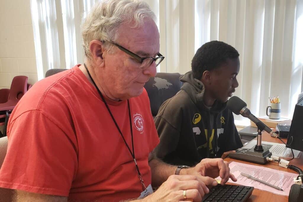 Volunteer Steve Ross (left) helps with a HAM radio broadcast at Loften High School.