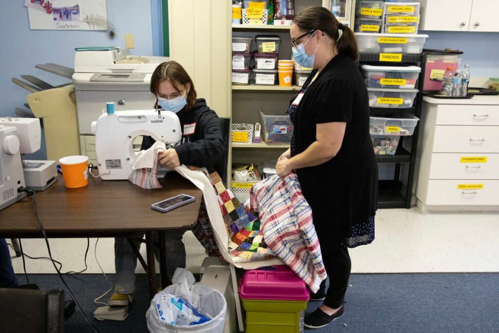 Carol Brake, right, helps Anastasia Carmichael, her boyfriend's 12-year-old daughter, quilt.