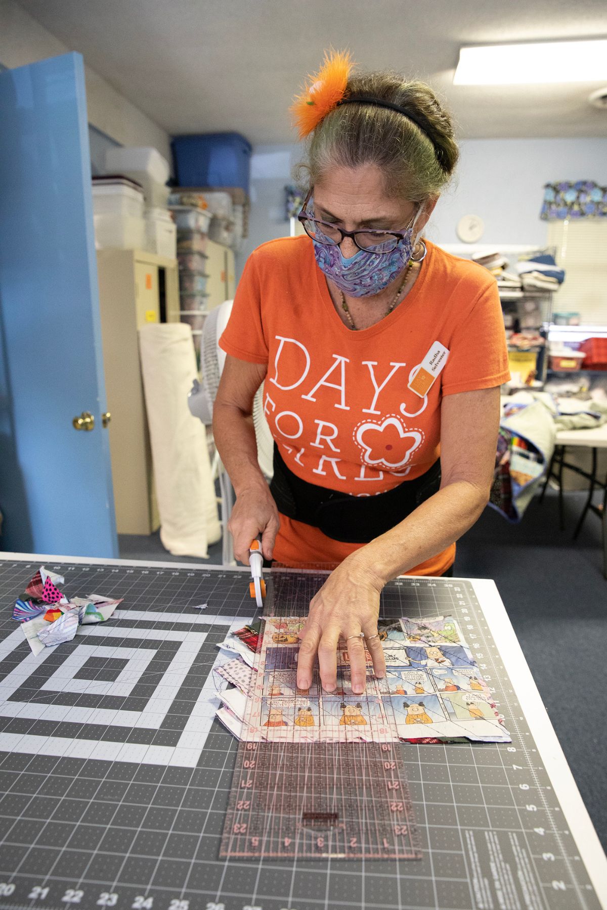 Event organizer Radha Selvester uses a ruler and a rotary cutter to remove excess fabric from a quilt square.