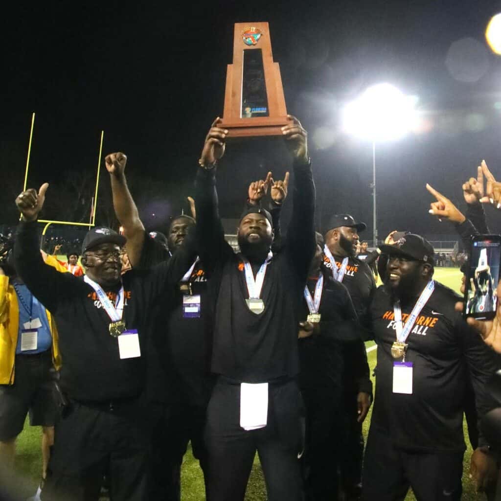 Hawthorne coaches celebrate with the state championship trophy on Saturday.