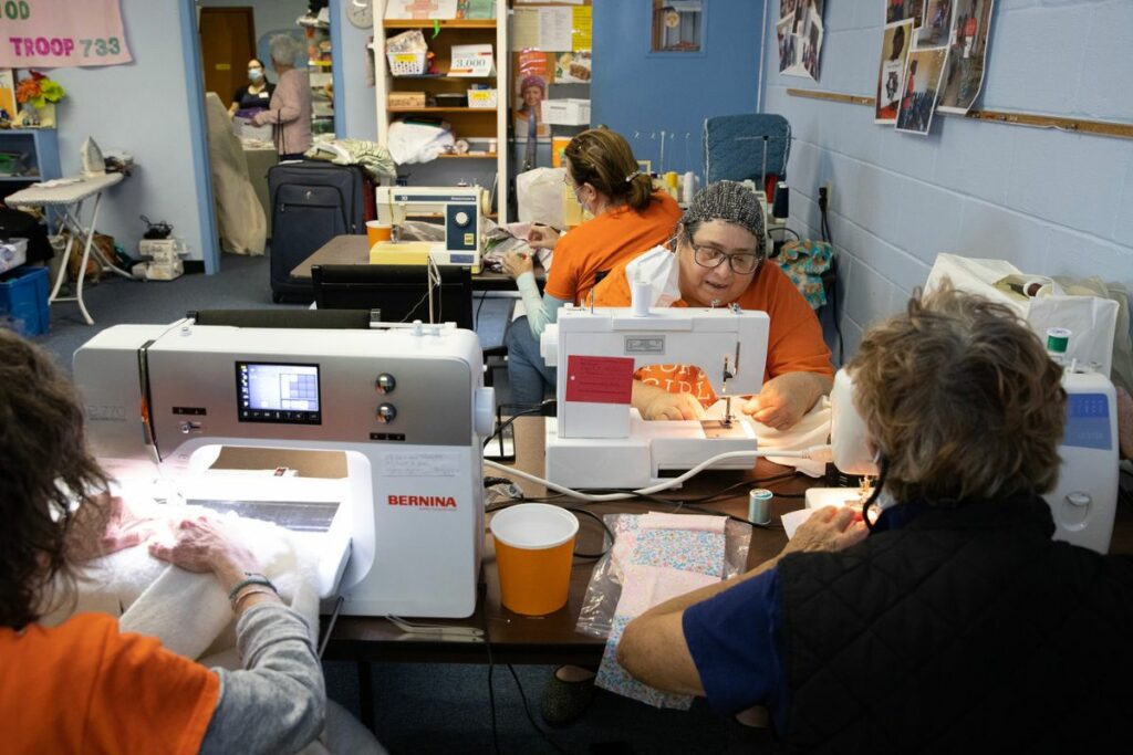Sheri Daar, wearing a knitted head covering, quilts together fabric squares.