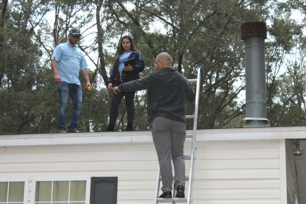 Worthmann Construction employees inspect free roof giveaway winner Sara Hannah's roof on Friday.