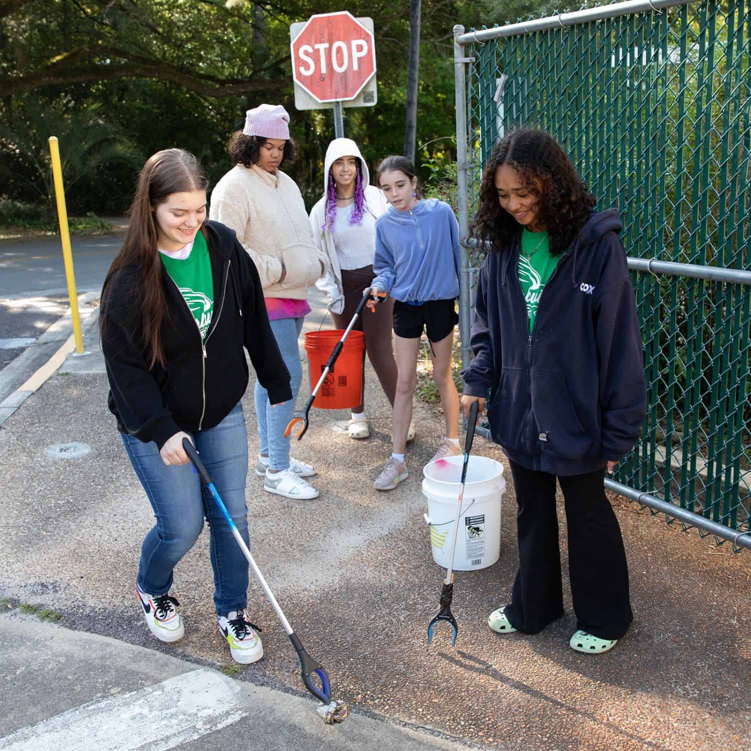 Jessie Whidden, a Westwood eighth grader, wields a trash picker to collect a piece of litter discovered near her school’s entrance.