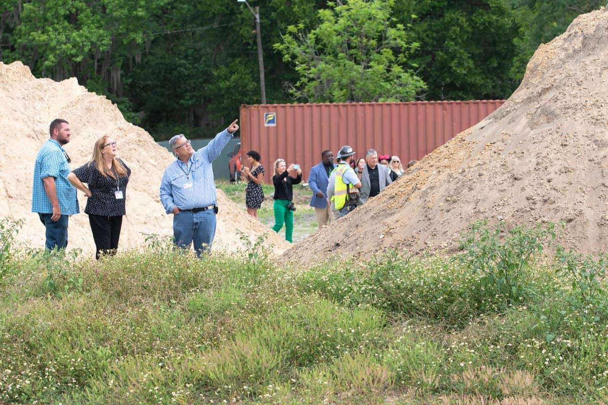 Attendees of the ceremony watch from afar as construction workers raise the first in a series of panels that will eventually form one wall of the main classroom building.