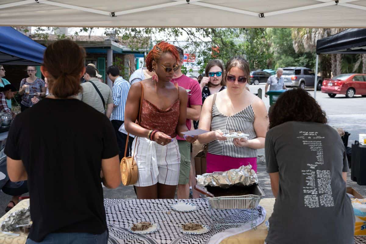 Festival attendees await samples of Palestinian food, which included kofta meatballs and mujadara, a mix of lentils and rice, prepared by Majd Afaghani, left, and Laila Fakhoury, right.