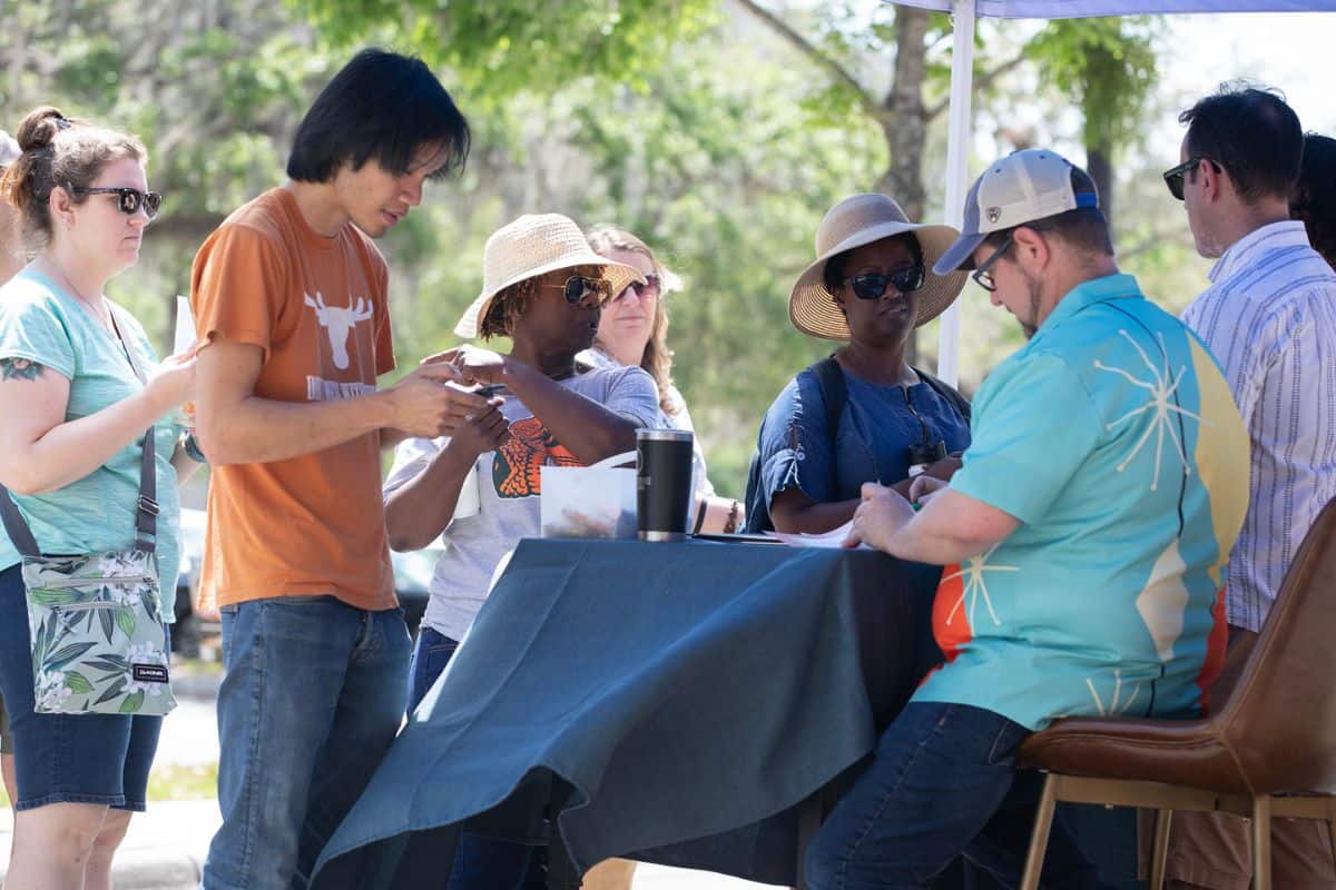 GGIC board member Jeremi Snook, in striped shirt, and GGIC president and CEO Lauren Poe, in hat, hand out food festival passports to registered patrons on Saturday.