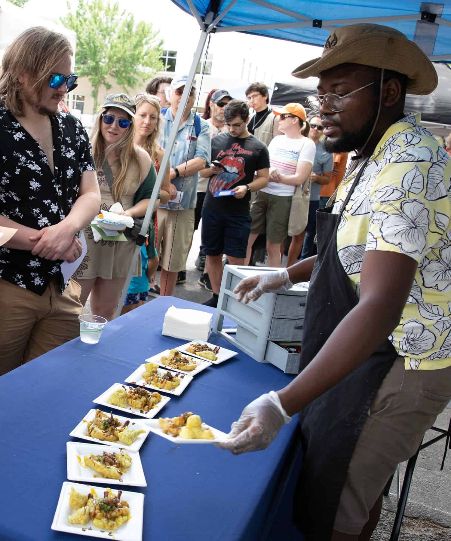Vaugel White of Frenzied Foods passes out food from Trinidad he cooked.