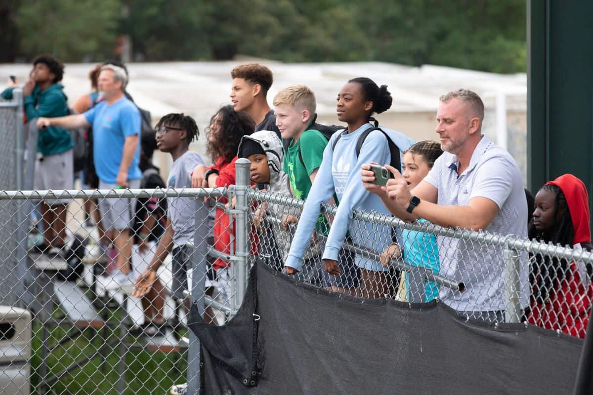 Westwood students and staff watch construction workers raise the wall from behind a fence separating their current, temporary school from the site of their future one.