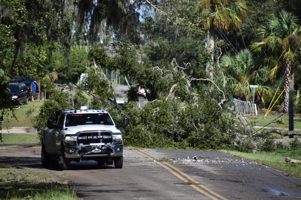 A police truck makes its way around a tree blocking the road into Steinhatchee, and the power line it has pinned down.