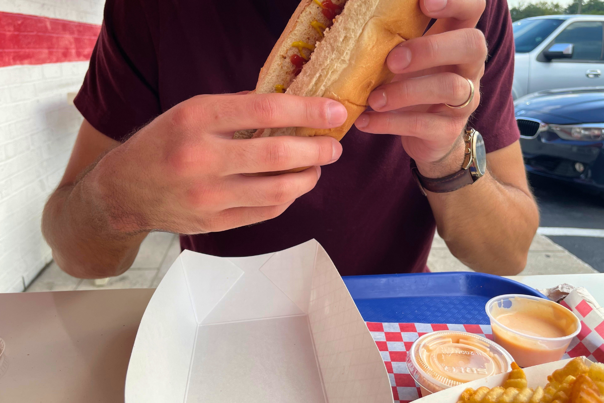 Man eating a hotdog at Big Mill's Cheesesteaks.