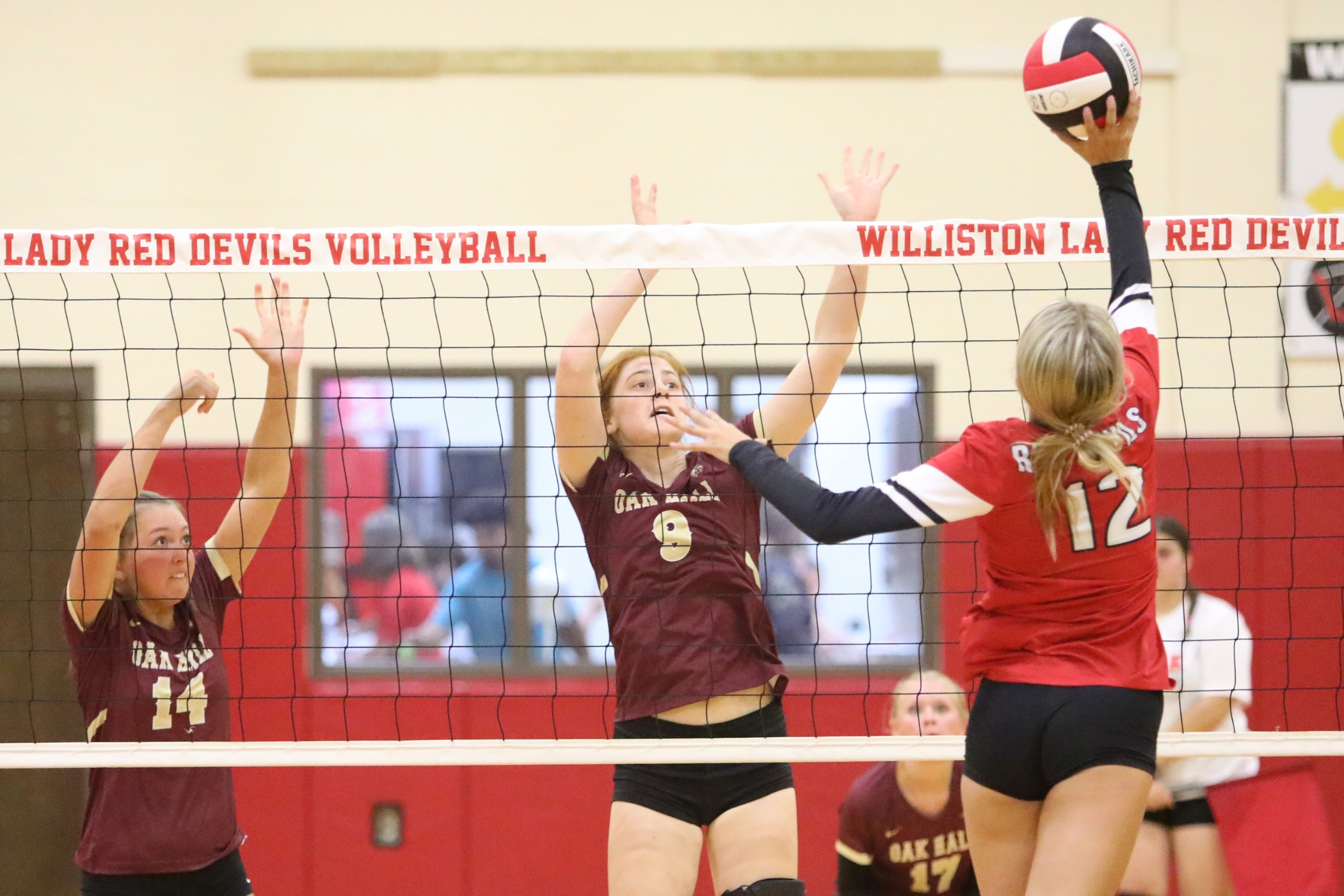 Williston's Ryleigh Hiers (12) with a hit against Oak Hall's Kendylle Bishop (14) and Pene Moser (9)