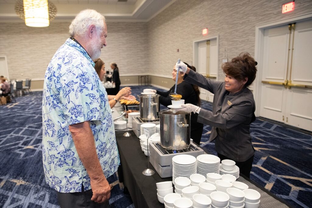 Hilton employee Usa Bailey, far right, ladles vegetable soup for an attendee of Thursday's Empty Bowls fundraiser.