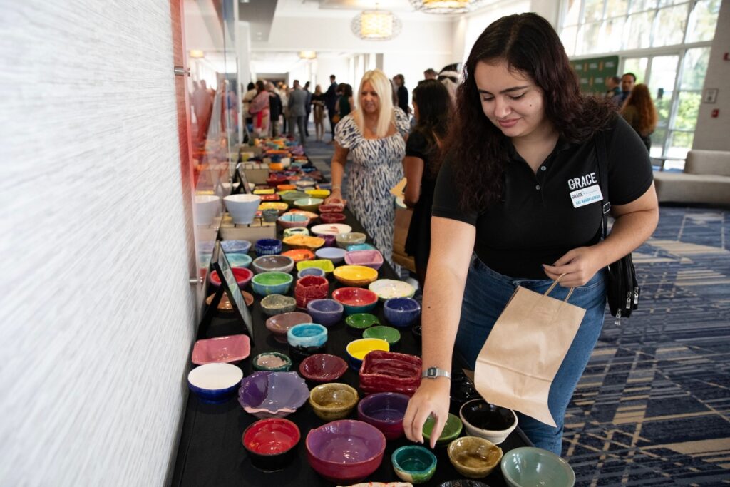 Nat Nandelstadt, a GRACE Marketplace employee, selects from the ceramic bowls created by local students and provided to attendees of the event.