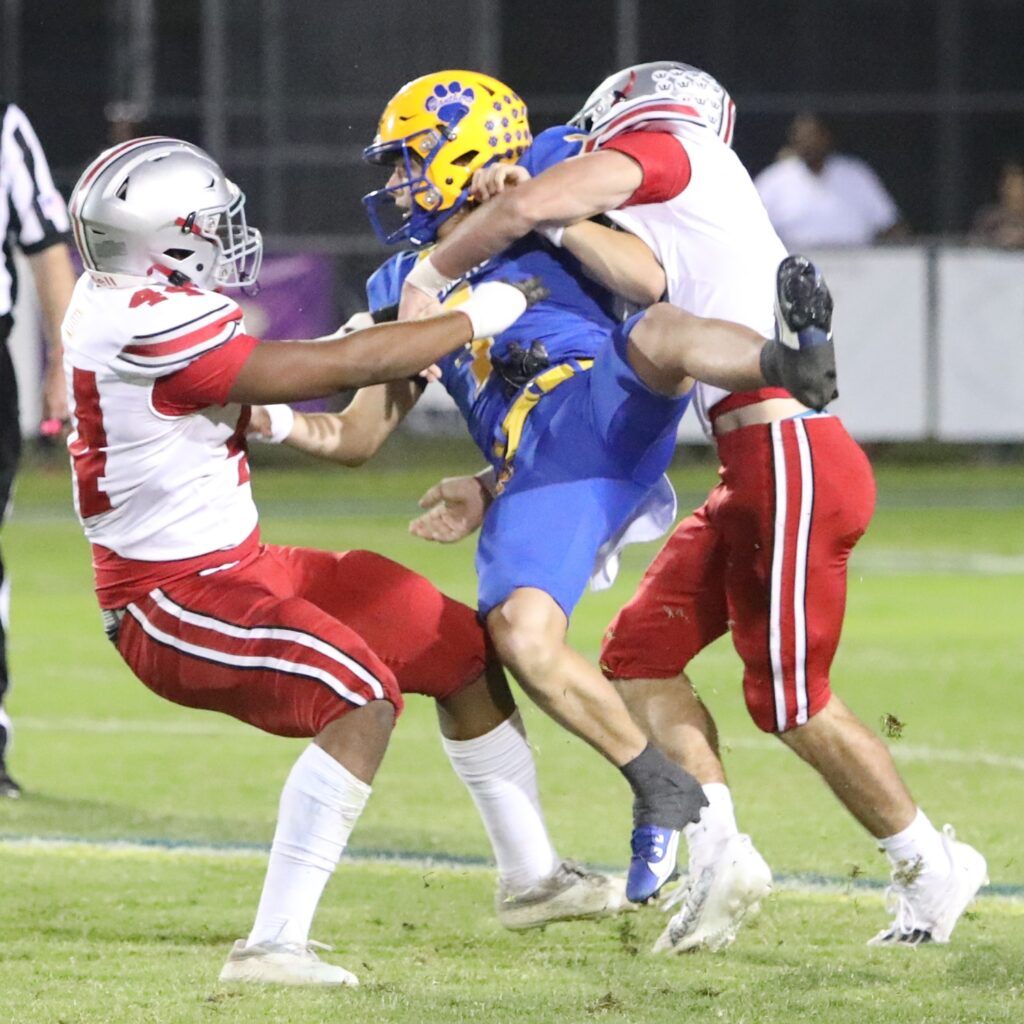 Newberry's Keil McGriff gets a pass off under pressure by Williston's Dontavious Kirby (left) and Timothy Taylor Jr. in the first quarter on Friday.