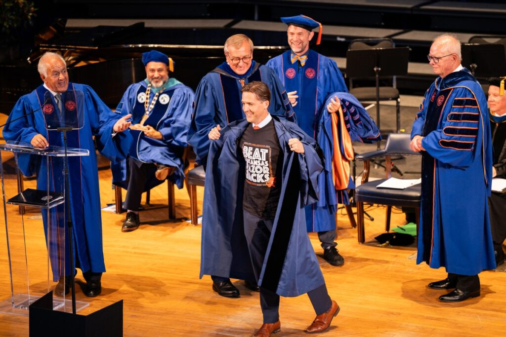 Ben Sasse with a Beat the Arkansas Razorbacks shirt on underneath his robe.