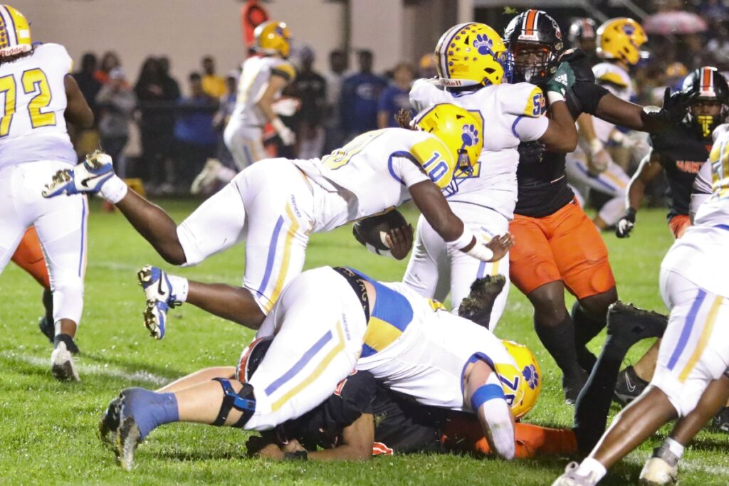 Newberry's Amarion Cason (10) tripped up by Hawthorne's Demetri Perry (under Newberry's Michaiah Neal) on Friday.