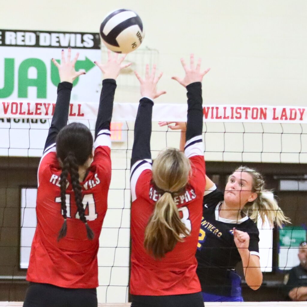 Newberry's Chloe Jones with a hit against Williston's Kai Gowland (14) and Carly Legler (13) on Tuesday.