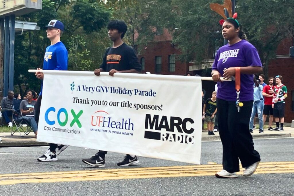 Holding a banner with the title sponsors at the start of A Very GNV Holiday Parade on Saturday.