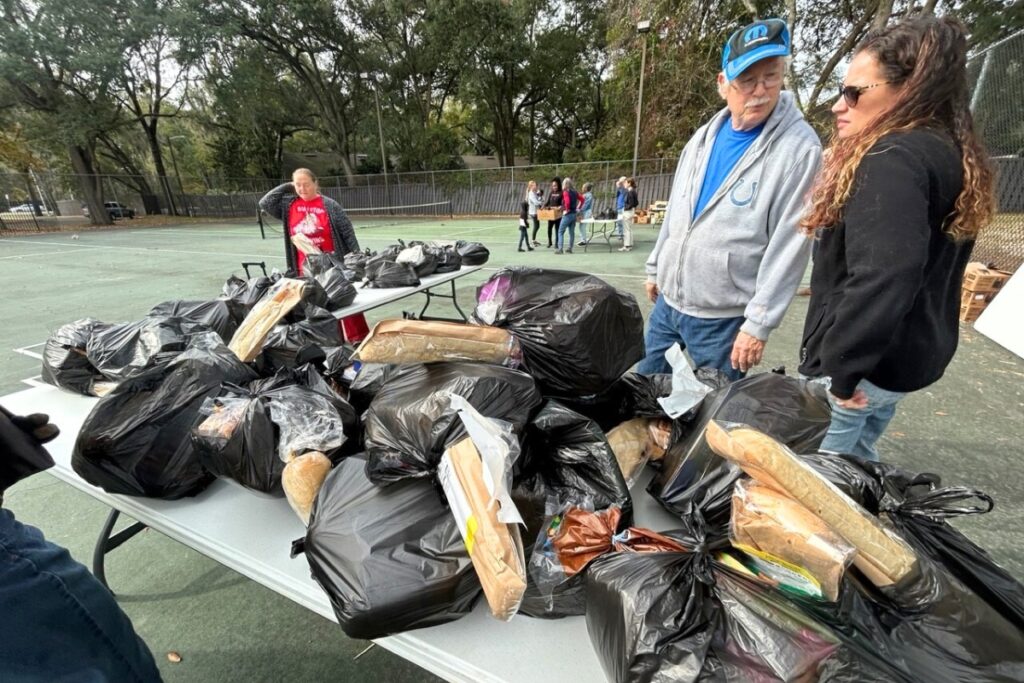 Katy Ping, Director of Missions at Trinity United Methodist Church and food distribution volunteer Greg McDermott, gather at one of the tables where food was begin given out during a recent distribution at Majestic Oaks.